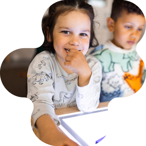 Barn på förskolan sitter med digitalt verktyg.