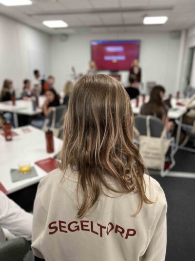 Elev på Innovitaskolan med ryggen mot kameran står i ett rum med flera andra elever, på tröjan står det Segeltorp.