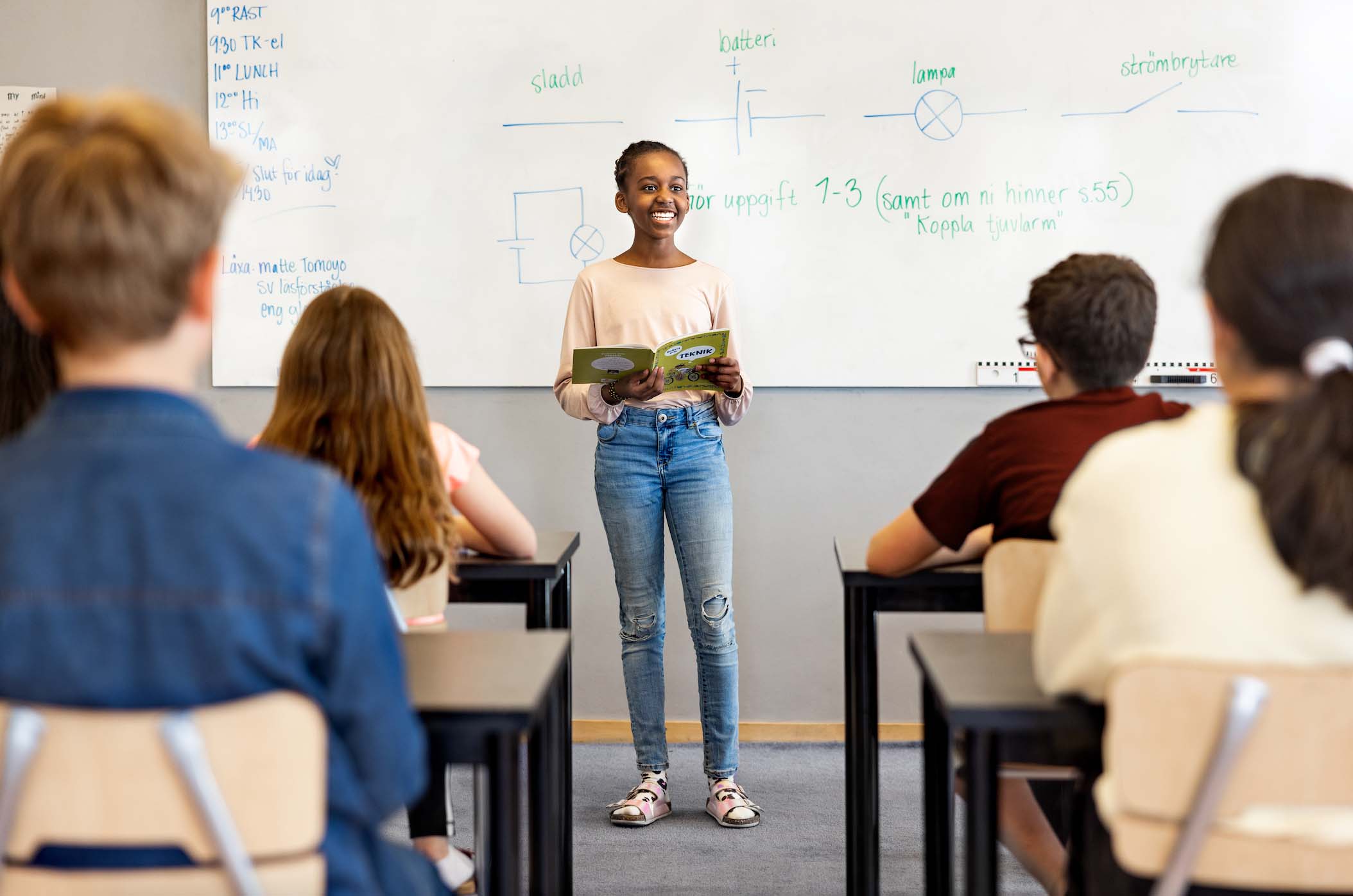 Elev på Innovitaskolan står framför sina klasskamrater och presenterar med en bok i handen.